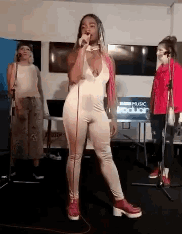 a woman in a white jumpsuit is singing into a microphone .