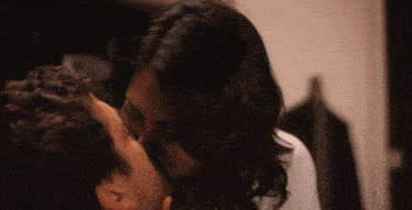 a man and a woman are kissing and the woman is wearing a white shirt