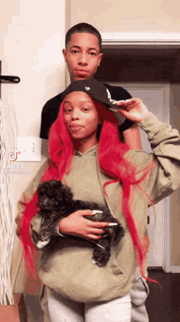 a man and a woman are standing next to each other holding a small dog .