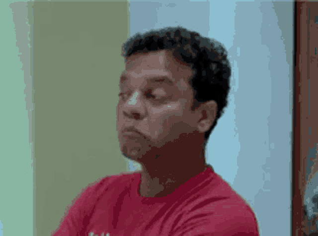 a man in a red shirt is making a face with his eyes closed