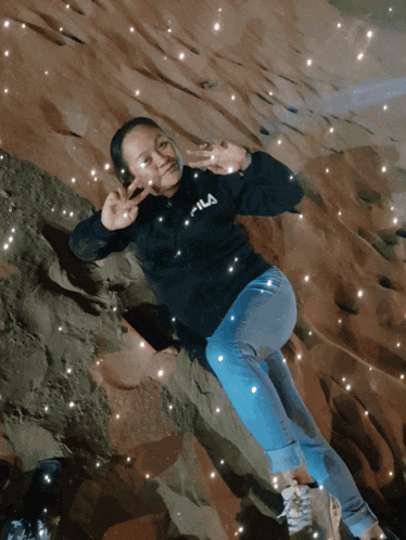 a woman wearing a fila sweatshirt is laying in the sand