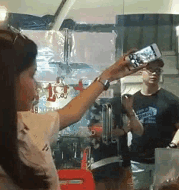 a woman is taking a selfie with a cell phone while a man looks on .