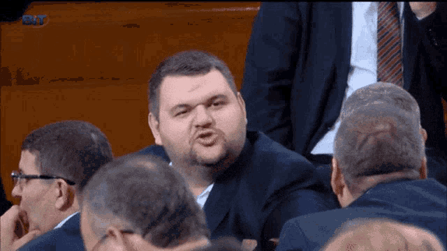 a man in a suit and tie is making a funny face in a crowd of people