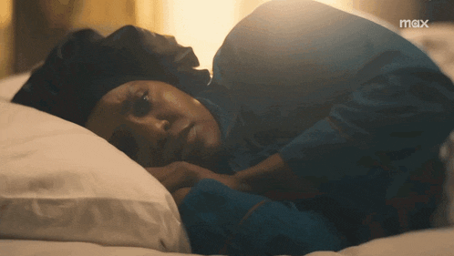 a woman is laying on a bed with a max logo in the background