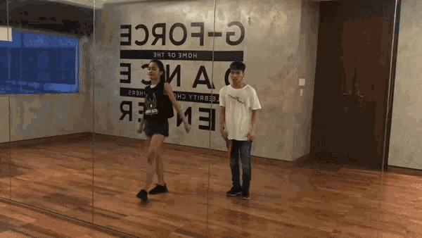 a boy and a girl are dancing in front of a sign that says " g-force "