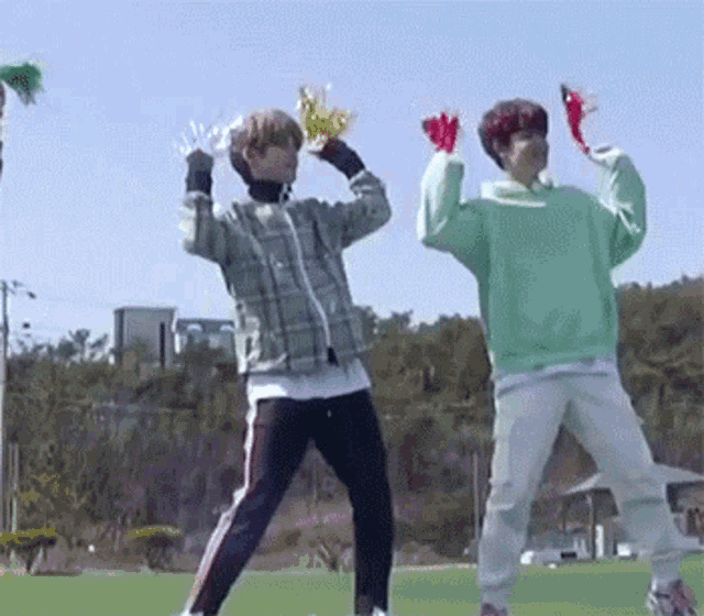 two young men are standing next to each other on a field holding pom poms .