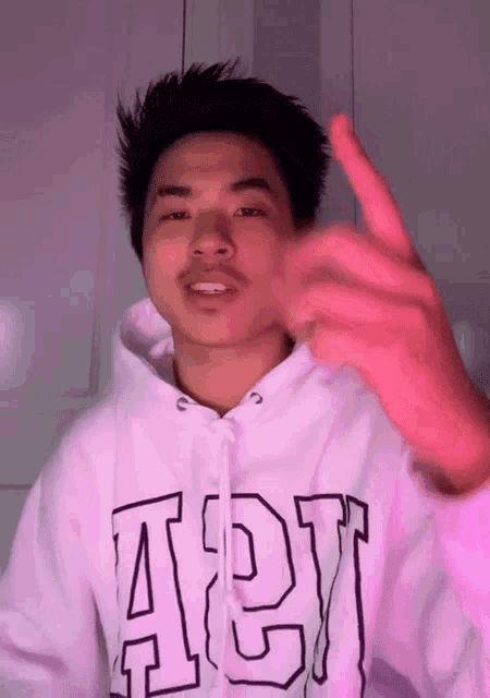 a young man wearing a white hoodie with the letter a on it .