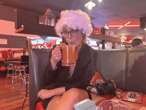 a woman wearing a white wig and glasses is drinking from a mug