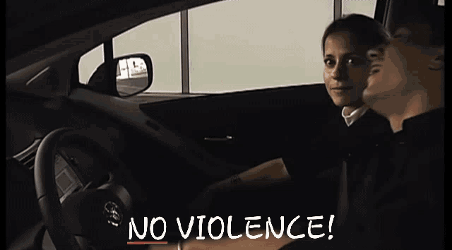 a man sitting in front of a sign that says " no violence " on it