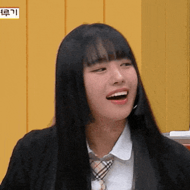 a girl with long black hair is wearing a school uniform and a tie .