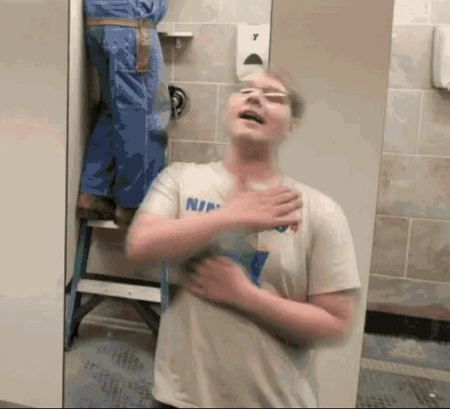 a man wearing a shirt that says nike stands in a bathroom