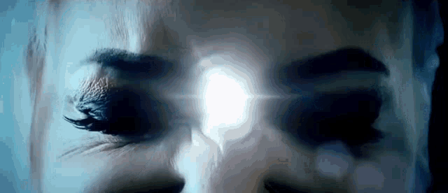 a close up of a woman 's eyes with a white light coming out of them .