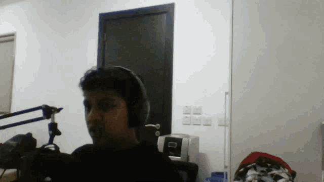 a boy wearing headphones stands in front of a microphone in a room