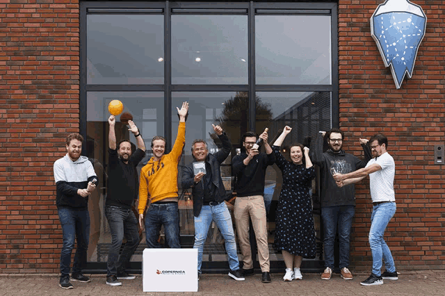 a group of people standing in front of a brick building with a box that says ' antwerpia ' on it
