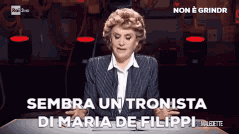 a woman sitting at a table with the words " sembra un tronista di maria de filippi "