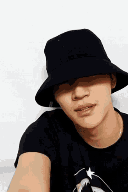 a man wearing a black hat and a black t-shirt with a shark on it