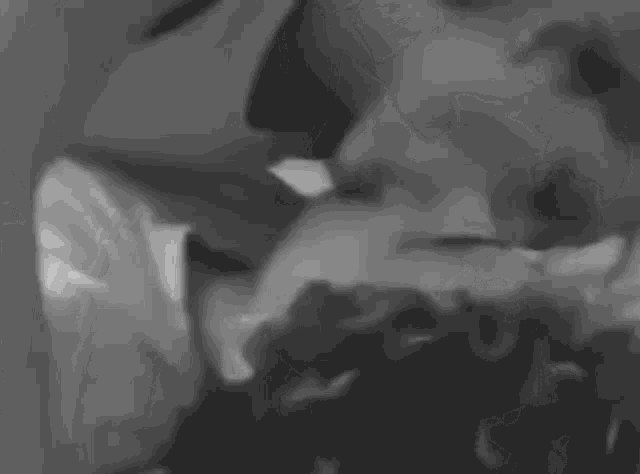 a black and white photo of a man and a woman kissing .