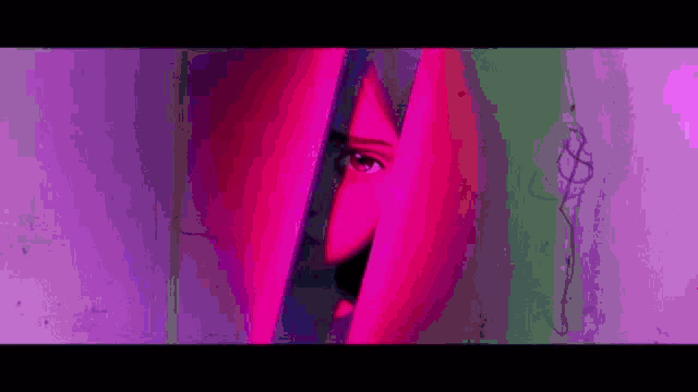 a close up of a woman 's face behind a pink and purple curtain .