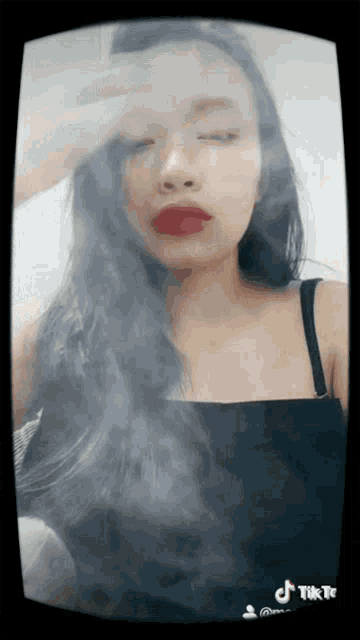 a woman with long black hair and red lipstick is smoking