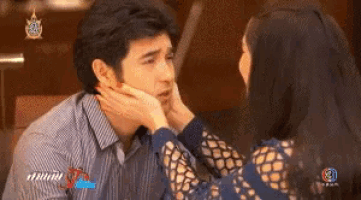 a woman is touching a man 's face while a man looks at her .