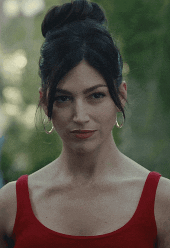 a woman in a red tank top and hoop earrings