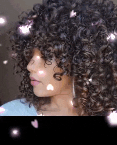 a close up of a woman 's face with curly hair and flowers coming out of her hair .
