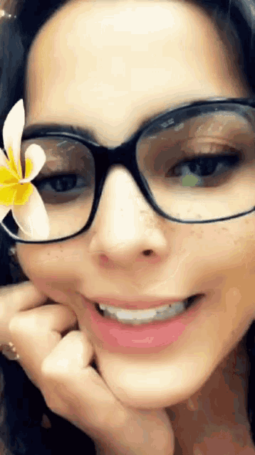 a close up of a woman wearing glasses with a flower in her hair