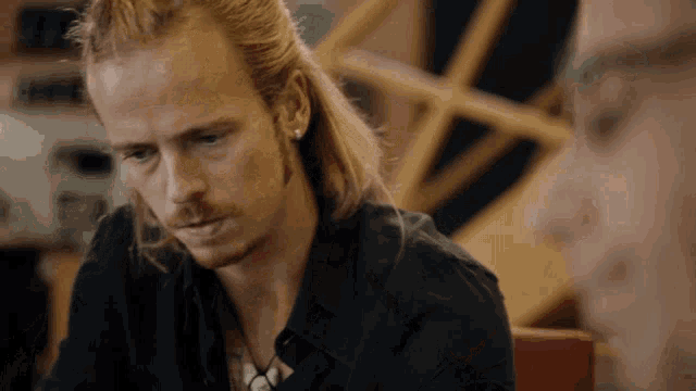 a man with long blonde hair and a beard is looking at something