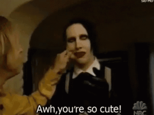 a man with black hair and red lipstick says aww you 're so cute .