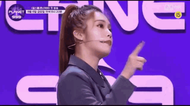 a woman in a ponytail is pointing at something in front of a sign that says planet 999 .