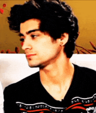 a young man with curly hair is wearing a black sweater