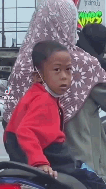 a little boy wearing a mask is sitting on a motorcycle .