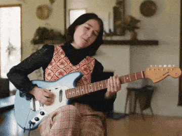 a woman playing a fender electric guitar in a living room