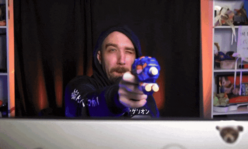 a man in a hoodie is pointing a blue toy gun