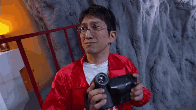 a man in a red jacket holds a camera