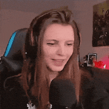 a woman wearing headphones is sitting in front of a microphone and smiling .