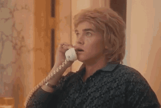 a man in a wig is talking on a telephone in a living room .