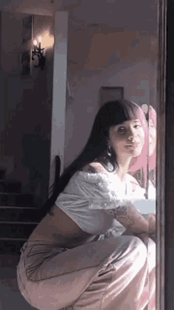 a woman is squatting down in front of a mirror .