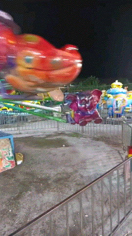 a ferris wheel at a carnival with a red car in the background