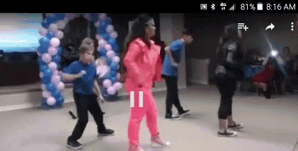 a group of children are dancing on a stage with balloons in the background
