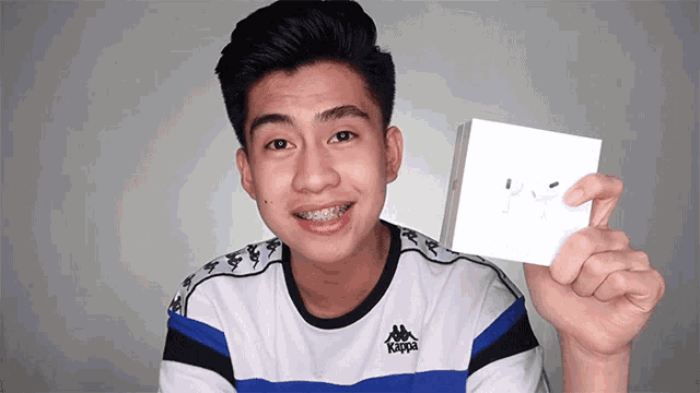 a young man in a kappa shirt holds up a box