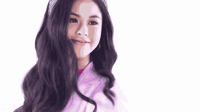 a young woman wearing a headband and a pink jacket is smiling and looking at the camera .