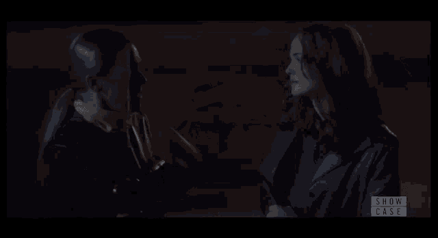 two women are standing next to each other in a dark room and the screen says show case