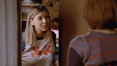 a woman wearing a t-shirt that says x is talking to another woman