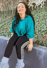 a woman wearing a blue shirt and black pants is smiling