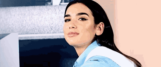a close up of a woman 's face wearing a blue shirt and a white collar .