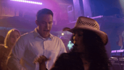 a man in a white shirt and a woman in a cowboy hat are dancing