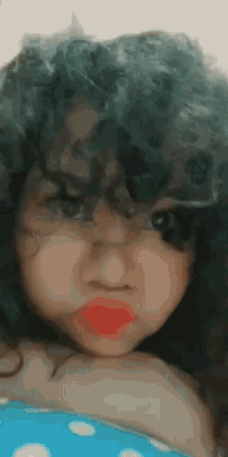 a girl with curly hair and red lipstick is making a face .