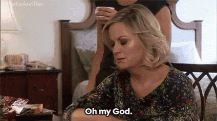 a woman is sitting on a bed holding a cup of coffee and saying `` oh my god . ''