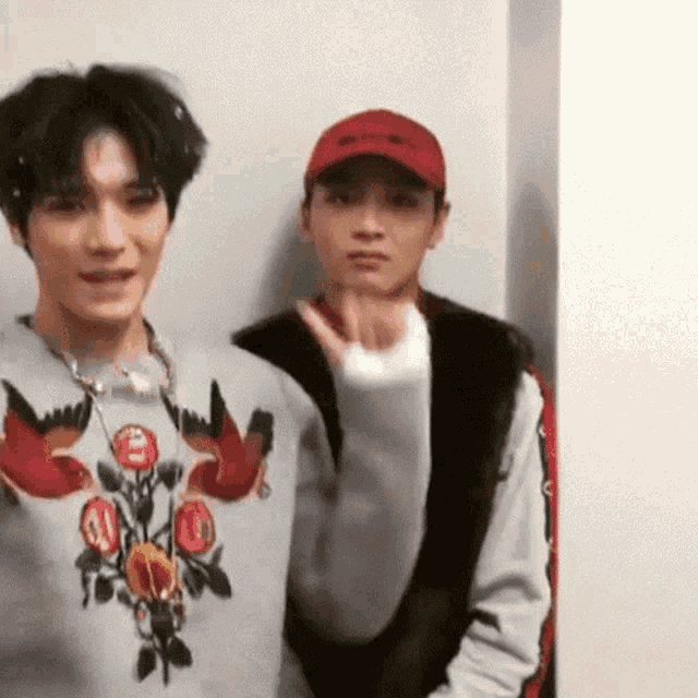 two men are standing next to each other and one of them is wearing a sweater with roses on it .
